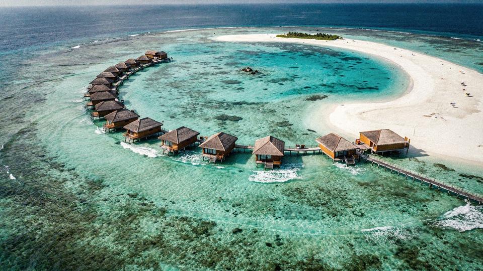 Overwater villas on a Maldives atoll photographed from above at midday