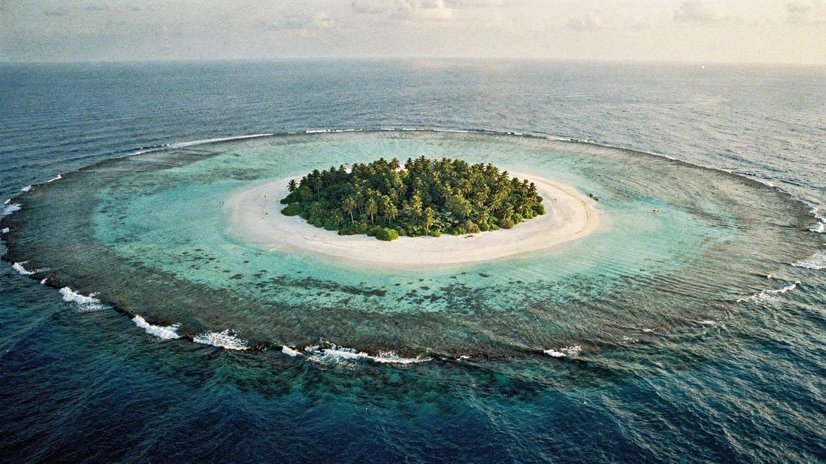 Aerial view of a Maldives atoll with a white sand island inside a turquoise lagoon